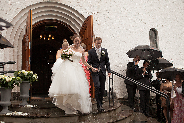 De nygifte kommer ut i regnet på kirketrappen