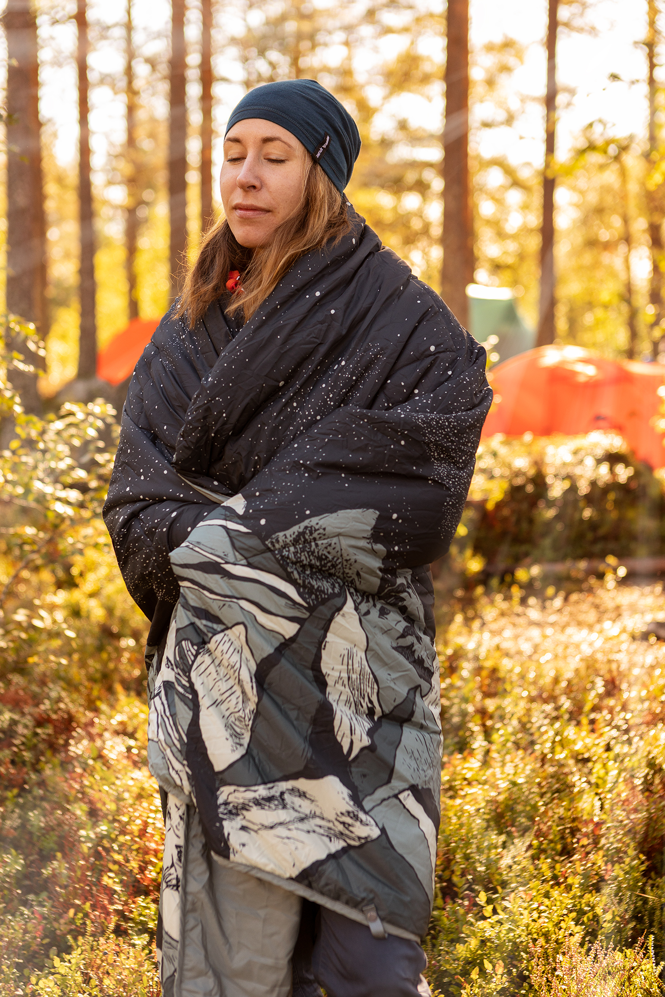 Bilde av en kvinne som nyter av morgensolen, utenfor sitt telt.